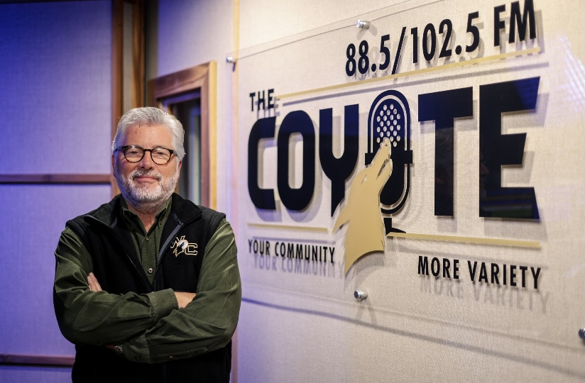 Dave in front of the Coyote Radio logo in studio.